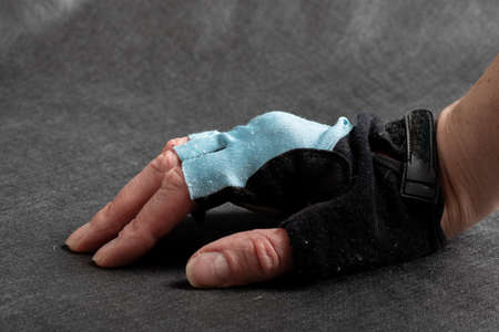 female hand in bicycle glove black and blue with open fingers close-up on a dark background.の写真素材