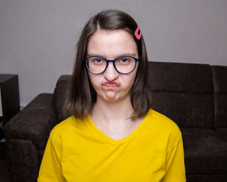Portrait of a beautiful displeased Caucasian girl in a yellow T-shirt, made an ugly lip shape,...