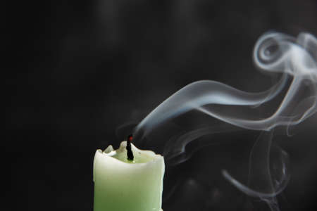 extinct light green candle with spectacular abstract smoke of a fanciful shape on a black background, close-up, abstraction.の写真素材