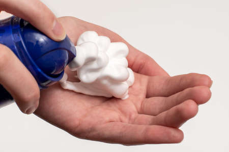 A close-up of a female hand squeezing foam in the palm of a hand. Place soap foam with foam on hand.の写真素材