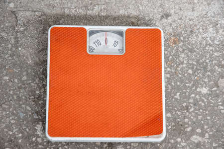 Top view of an old orange mechanical scale standing on a stone floor. Scales used a lot. The concept of losing weight, healthy livingの写真素材