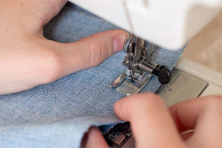 Close-up of sewing on a sewing machine, hands guide the fabric. The concept of creativity, hobby.