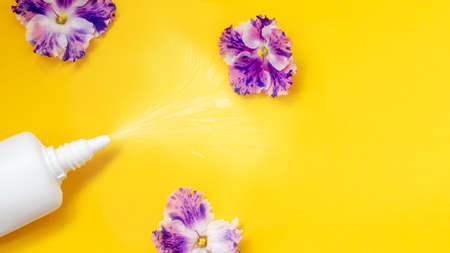 Flower allergy concept. White spray can with violet flowers on a yellow background. Creative flat lay, copy space.の写真素材