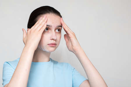 A close-up of a girl's face in acne uses a foaming cleanser. The girl is worried about acne. Teenage skin care concept, copy spaceの写真素材