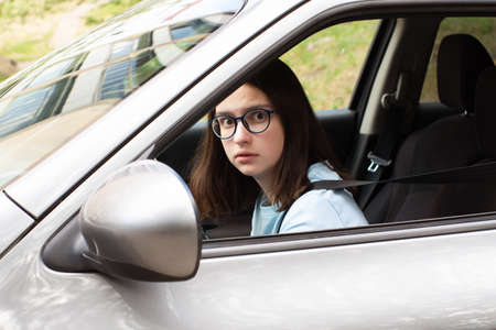 Closeup of a young girl driver. Girl learns to drive a car. Fear of traffic, traffic jams. Stress from driving a carの写真素材