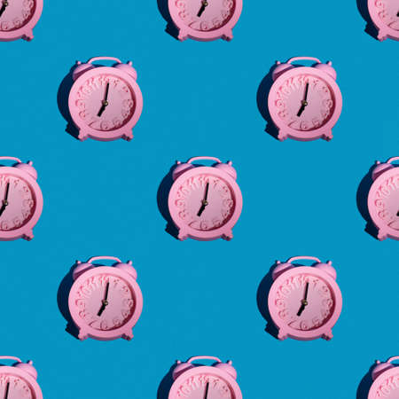 Fashionable pattern with a pink clock on a blue background, repeating wallpaper with a minimalist seamless layout. The concept of the morning rise, time for breakfast.の写真素材