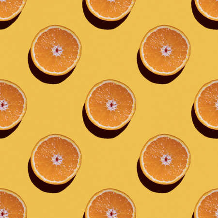 Colorful fruit seamless pattern of halves of oranges on a yellow background. Top view.