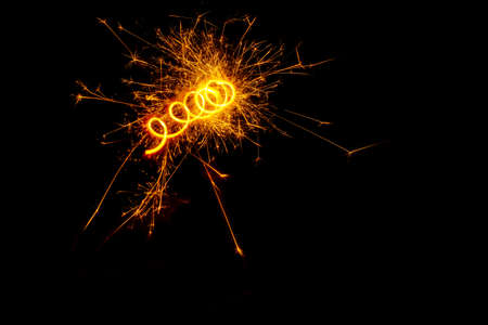 A spiral of light from a sparkling burning sparkler or salute on a black background. Holiday...