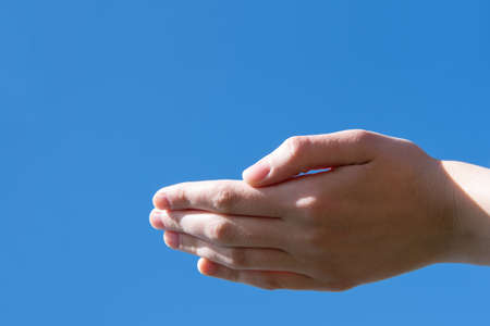 Empty open female hand blocking gesture against a blue sky. Can be used as a basis for design, copy spaceの写真素材