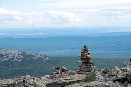 Stacked pyramid stones that mark a mountain trail, a landmark for hiking, against the backdrop of...