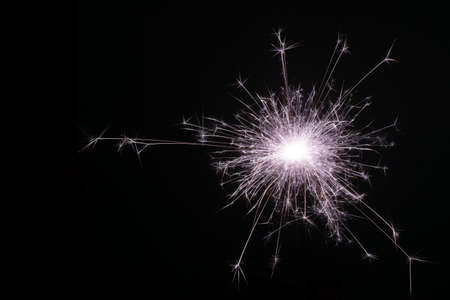 Happy New Year, sparkling burning sparkler or salute on a black background. Holiday concept, background, copy space.の写真素材