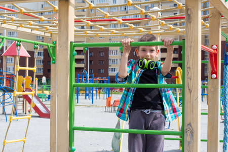 happy boy climbing into colorful activity tower on the playground, children development and...