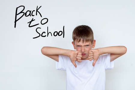 Portrait of unhappy, unhappy boy making thumbs down hand gesture. The boy does not want to study, does not want to go to school. Learning concept, Back to school. Copy spaceの写真素材