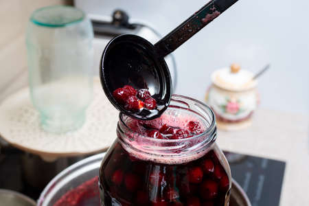 Making homemade cherry jam. Jam is poured into storage jars, selective focus. Healthy food concept. Sweet summer dessertsの写真素材