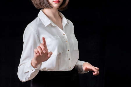 Business young woman pointing her finger at you, isolated on black background. Business concept.の写真素材