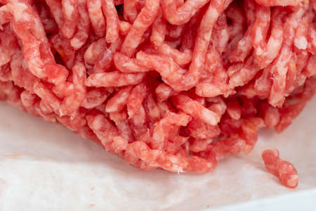 Close-up of minced pork and beef rolled in a meat grinder, minced meat for cooking on baking paper....