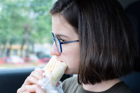 Young beautiful woman eating fast food, close-up. Unhealthy food concept, fast food.