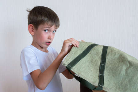 Portrait of a curious boy peeking behind an object hidden behind a green cloth. Concept of child...