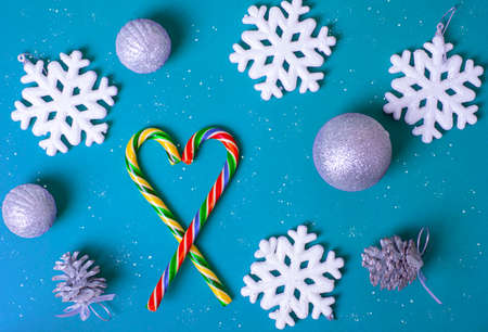 Heart shape with red Christmas candy canes, white large snowflakes, silvery balls on a dark blue...
