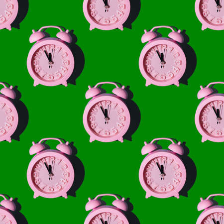 Seamless pattern with pink clocks on a green background, repeating wallpaper with minimalistic seamless layout. New Year at midnight concept. Can be used as background, wrapper, textile elementの写真素材