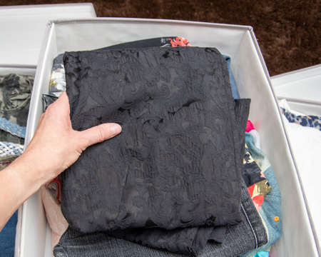 Womens hands folds clothes, things in storage boxe, top view, close-up. Clothes storage concept....