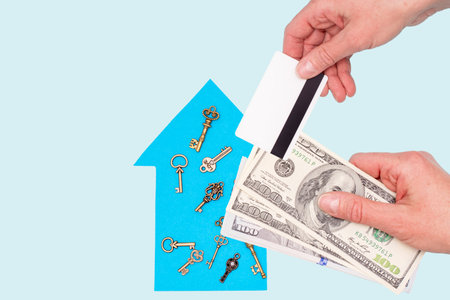 The concept of a new home, mortgage, loan. oman's hand holds dollars and hand holds a credit card...