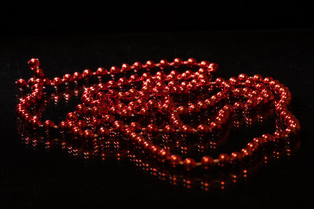 Red shiny beads and reflection on black background, copy space, top view. Can be used as a design...