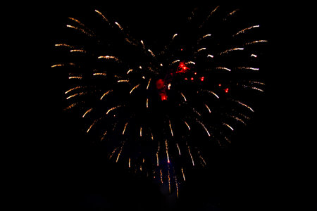 Colorful red fireworks in the shape of a heart isolated on a dark background. Bright yellow and red...