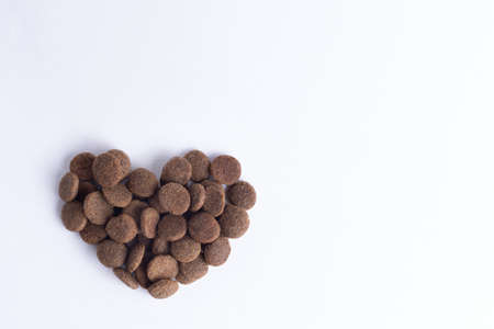 Dry pet food for dogs and cats in the shape of a heart isolated on white background, copy space, top view. The concept of love for pets. Healthy pet food conceptの写真素材