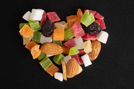 Diet food concept for Valentines Day. Dried fruits and nuts in the shape of a heart isolated on a black background, top view, close-up, macroの写真素材