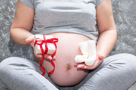 Pregnant woman feeling happy at home while taking care of her child. Pregnant woman holding baby...
