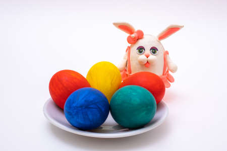Happy Easter concept. Hand-painted Easter eggs and a hand-made plasticine bunny on a white backgroundの写真素材