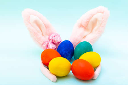 Happy Easter concept. Hand-painted Easter eggs and pink bunny ears on a blue background, close-upの写真素材