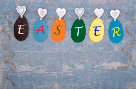 Easter greeting card made of Easter multi-colored paper eggs hanging on a rope with the inscription EASTERの写真素材