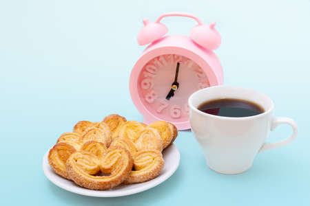 White cup of steaming hot black coffee or hot chocolate, freshly baked heart shaped cookies and pink...