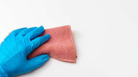 A hand in a blue latex glove holds a pink microfiber rag isolated on a white background, copy of the prastranst, banner, close-up. General or regular cleanup. Commercial cleaning company.の写真素材
