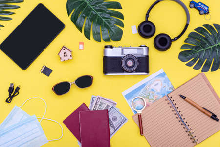 Camera glasses notepad for planning a passport card money headphones tablet and masks on a bright yellowの写真素材