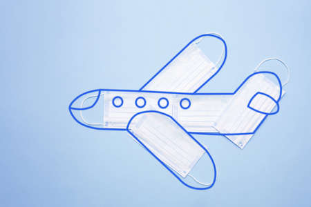 Airplane model made of protective masks with an outlined outline on a blue background. Safe travel by plane concept. New normal concept.の写真素材