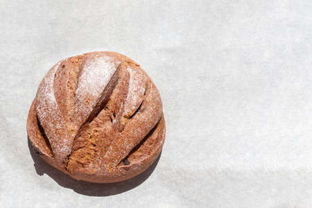 Freshly baked homemade rye round raisin bread on baking paper, top view, copy space. Healthy food conceptの写真素材