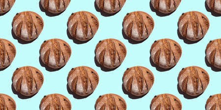 Fresh homemade rustic rye round bread seamless pattern isolated on blue background, top view. Can be used as food background, base for textiles, packagingの写真素材