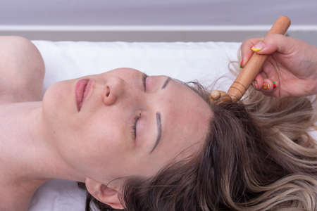 Massage the roots of the girls hair using the wooden roller massager, close-up. Massage hair roots...