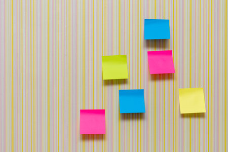 Many blank colorful memory stickers on striped multicolored background. Blank space on multi-colored...