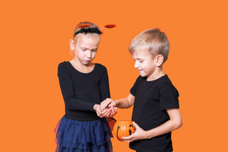 Childrens trick or treat is a Halloween tradition. Boy and girl holding an orange pumpkin-shaped basket with treatsの写真素材