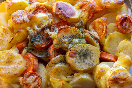 Homemade baked potatoes with fried crust, carrots, onions, spices, herbs close-up, top view. Dietary natural foodの写真素材