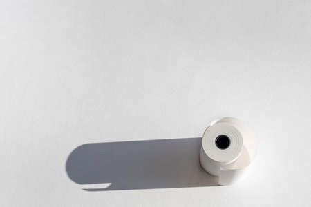 Roll of cassette paper tape with shadow on white paper. Roll of cash register tape, slip receipt paper rollの写真素材