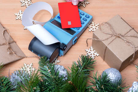 Cashiers hand holding a credit card above an EDC machine or cash register to pay Christmas gifts....