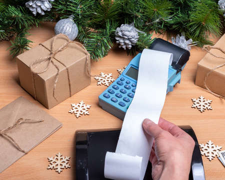 Hand holding a blank long cash register receipt from the cash register on the counter with gift...