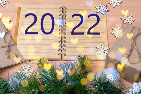 Happy new year 2022. Open diary with the date 2022 on a festive table with gifts in handmade boxes,...