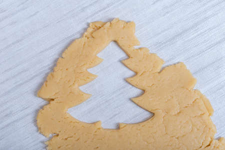 Christmas and New Years tradition. Family home bakery. Cooking traditional gingerbread cookies. The shape of a Christmas tree cut from raw dough. Christmas cookiesの写真素材