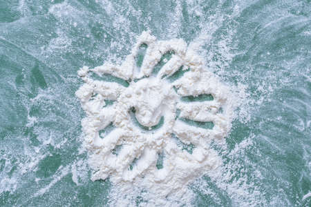 Drawn sun on flour on the table. The child plays with flour. Tactile exercises for childrens fingers.の写真素材